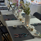 Dining table setup with pliers, candles, and flowers in a kitchen.