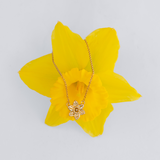 Gold necklace with a flower pendant on a yellow flower against a light gray background