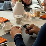 Two people at a table with crafting materials and tools, including scissors and beads.