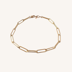 A gold paperclip chain bracelet with a lobster clasp, displayed on a clean off-white background.