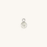 A small round diamond charm in silver, centered on a light cream background.