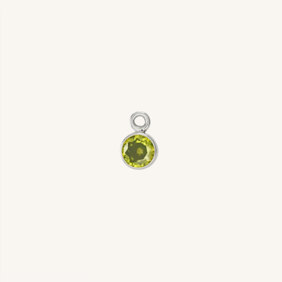 A small round peridot charm in silver, centered on a light cream background.