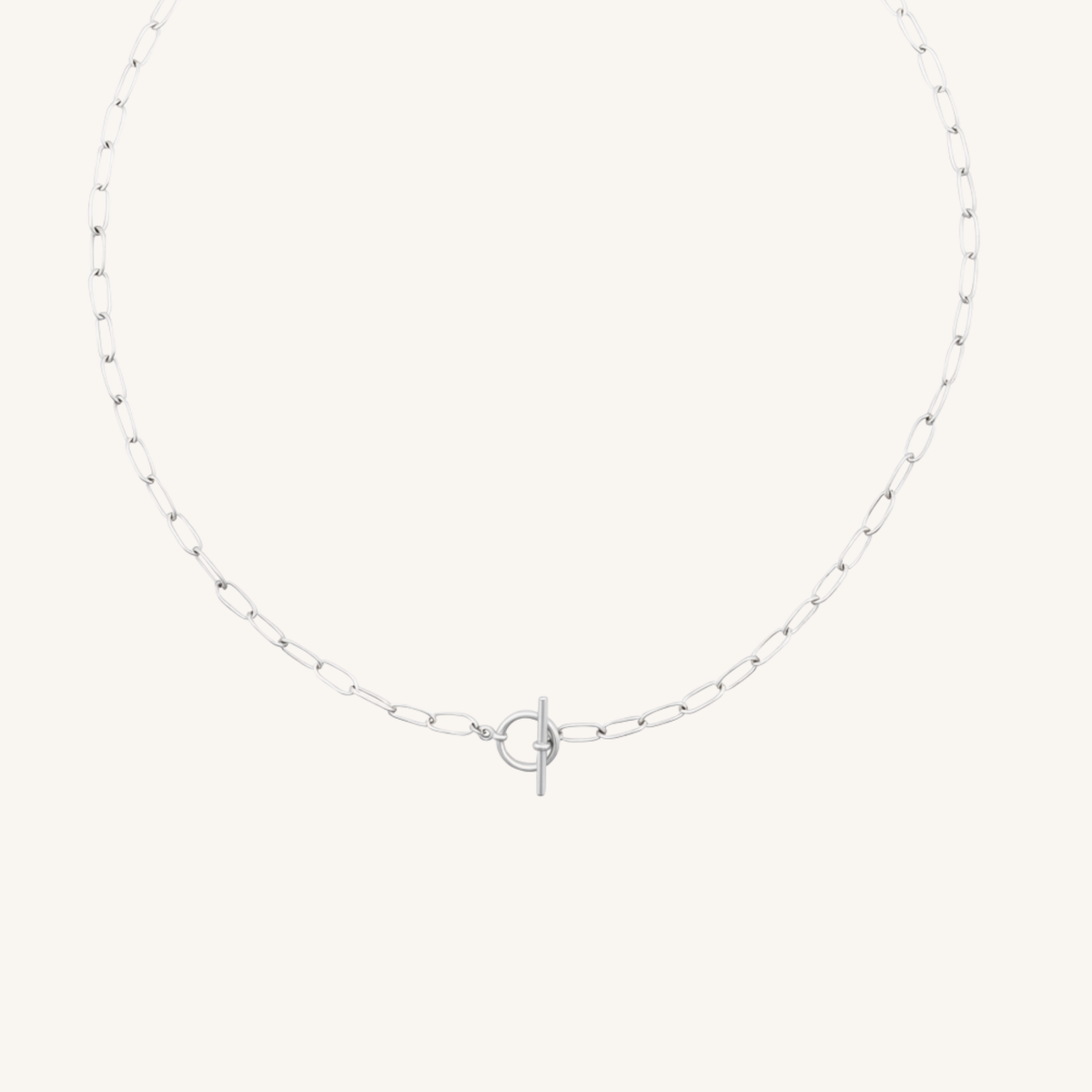 A delicate silver paperclip chain necklace with a central interlocking O-ring and T-bar clasp, displayed on a clean, solid off-white background.