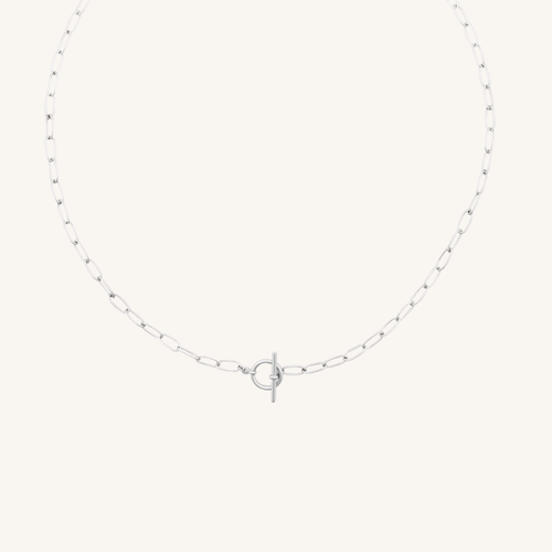 A delicate silver paperclip chain necklace with a central interlocking O-ring and T-bar clasp, displayed on a clean, solid off-white background.