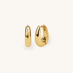 Gold hoop earrings on a light beige background