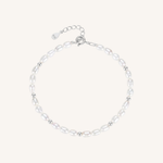 A delicate baroque pearl bracelet with small silver spacer beads and a silver lobster clasp with an extender chain, displayed on a light cream background.