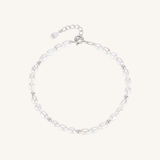 A delicate baroque pearl bracelet with small silver spacer beads and a silver lobster clasp with an extender chain, displayed on a light cream background.
