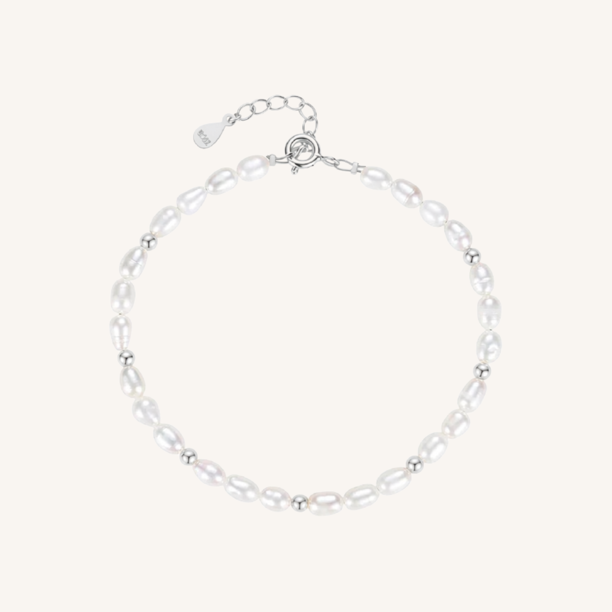 A delicate baroque pearl bracelet with small silver spacer beads and a silver lobster clasp with an extender chain, displayed on a light cream background.