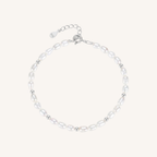 A delicate baroque pearl bracelet with small silver spacer beads and a silver lobster clasp with an extender chain, displayed on a light cream background.