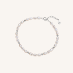 A delicate baroque pearl bracelet with small silver spacer beads and a silver clasp, displayed on a light cream background.
