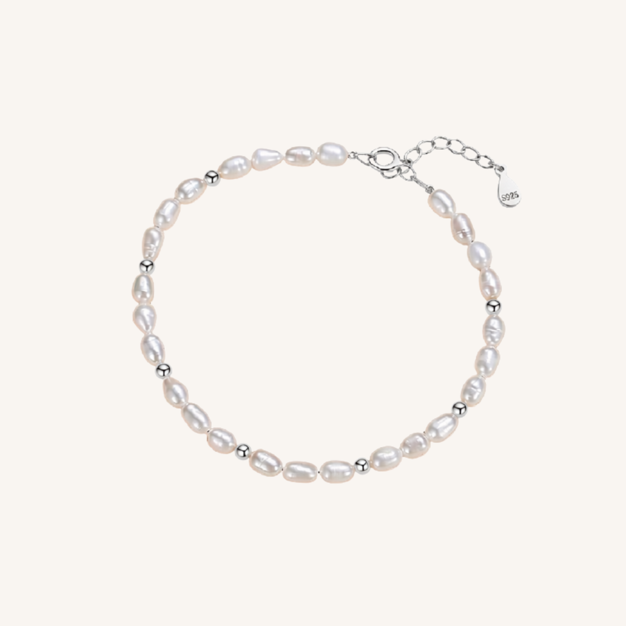 A delicate baroque pearl bracelet with small silver spacer beads and a silver clasp, displayed on a light cream background.