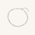 A delicate baroque pearl bracelet with small silver spacer beads and a silver clasp, displayed on a light cream background.