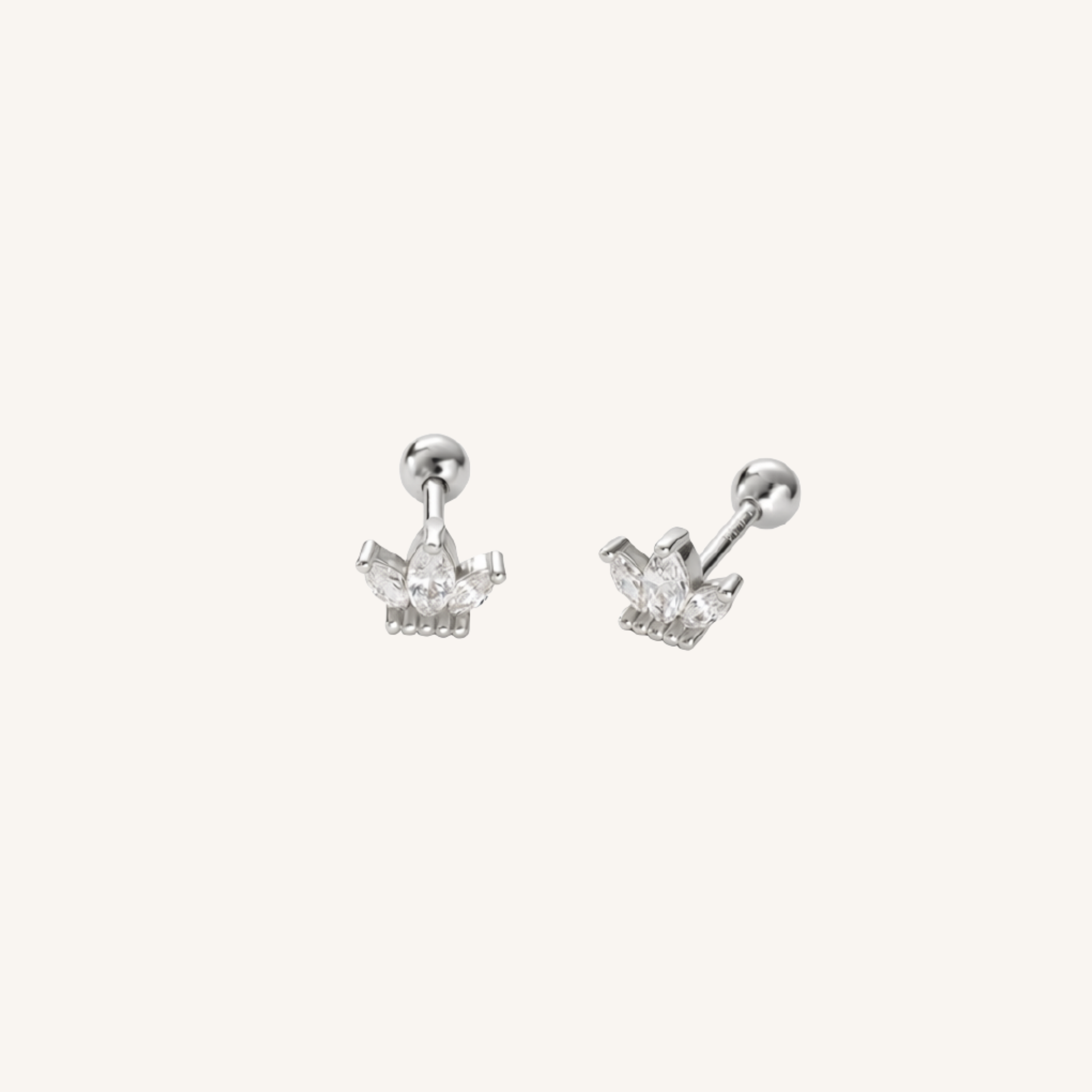 A pair of silver crown stud earrings with clear gemstones, shown from two angles on a light cream background.