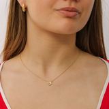 Close-up of a woman wearing a gold necklace with a pendant.