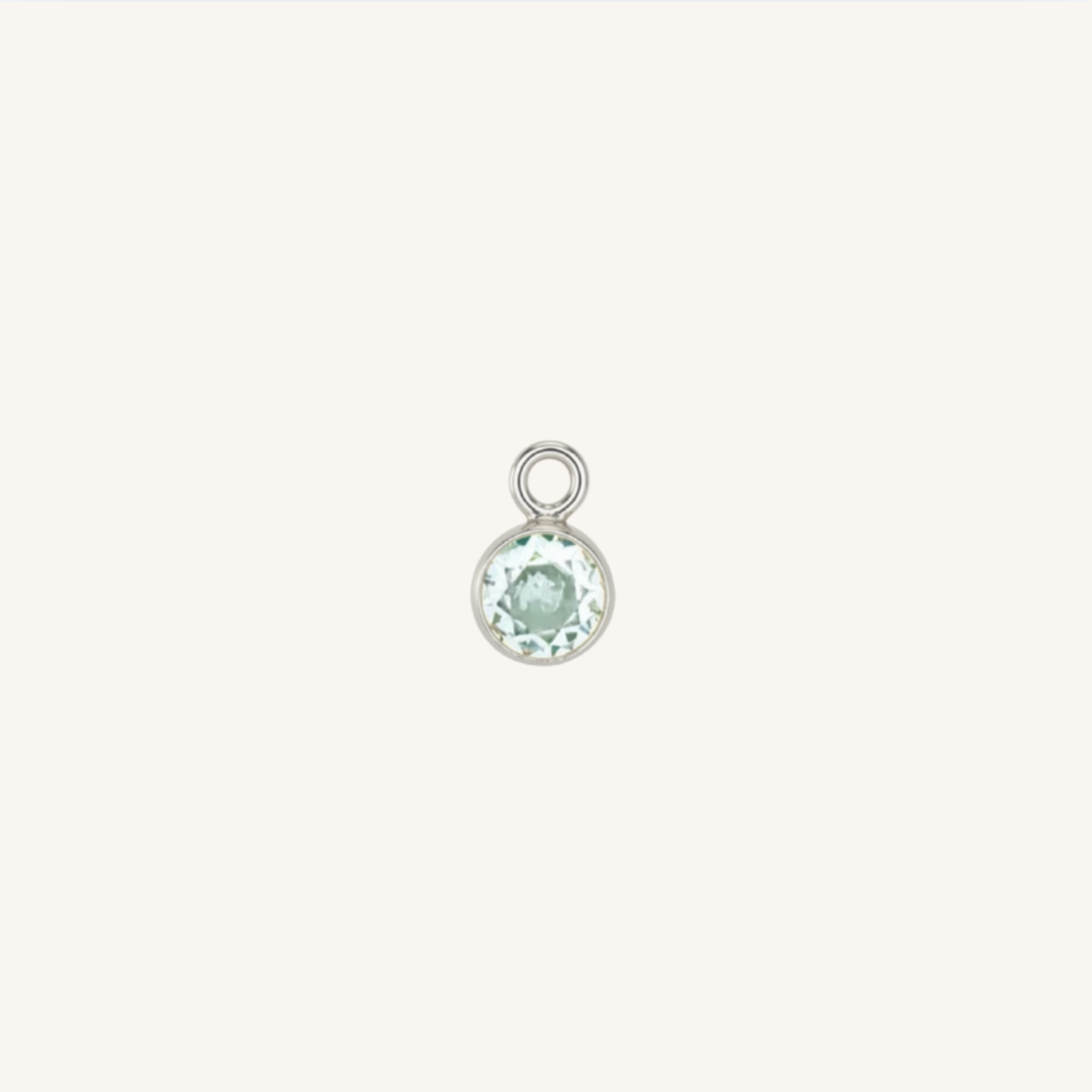 A small round turquoise charm in silver, centered on a light cream background.