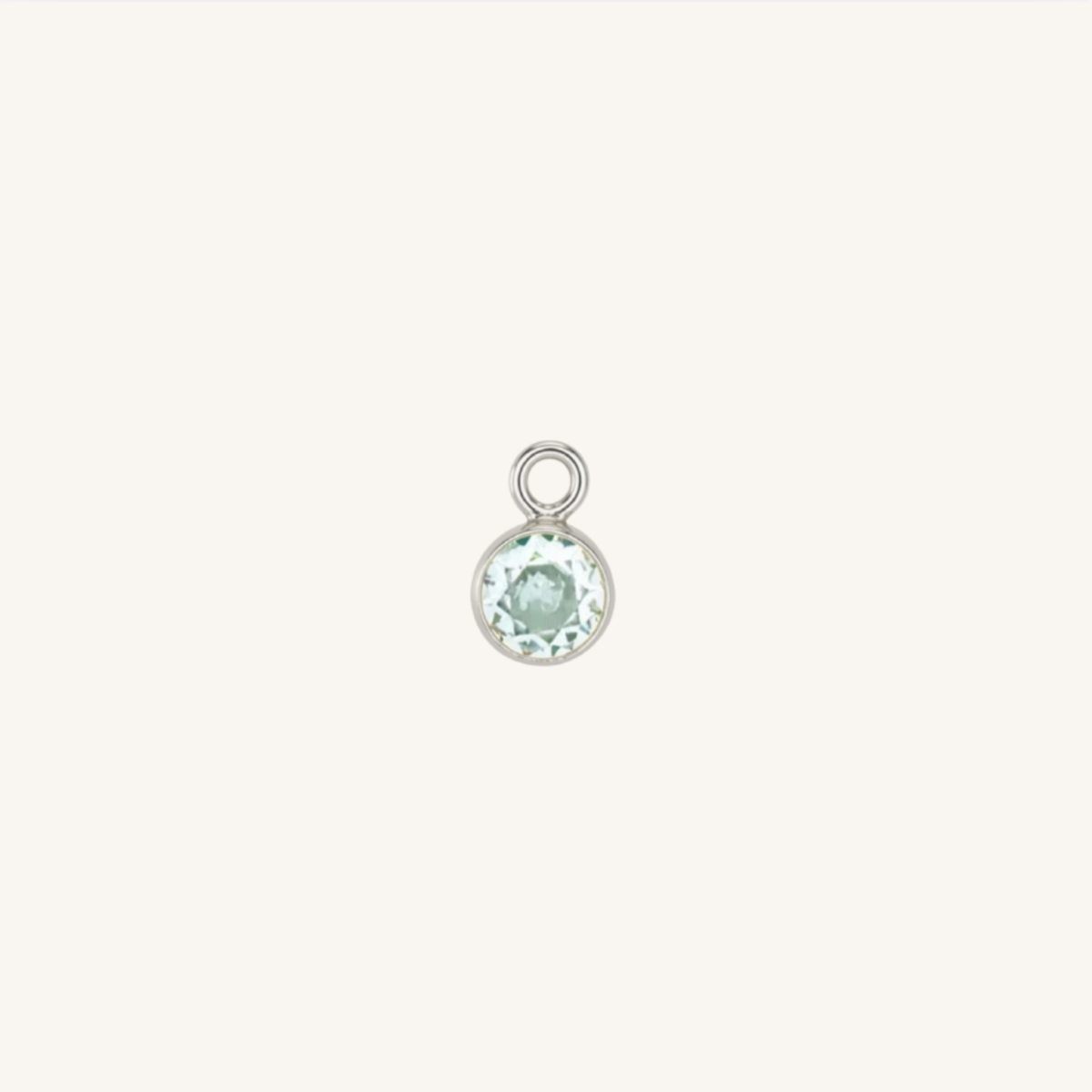 A small round turquoise charm in silver, centered on a light cream background.