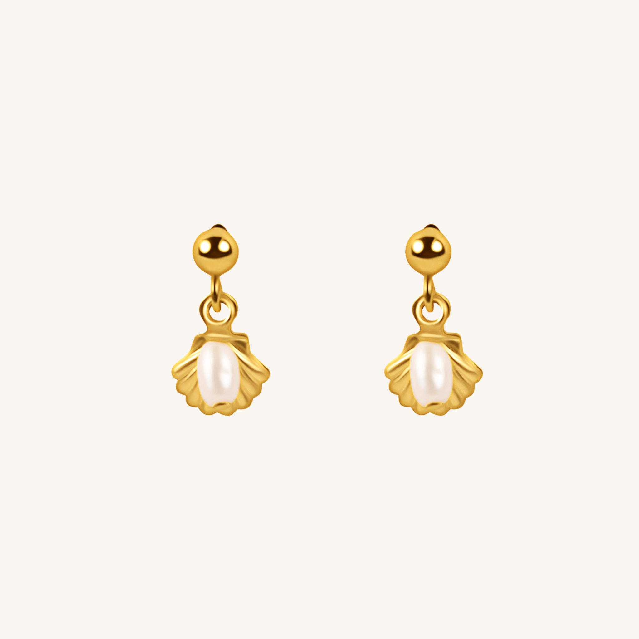 A pair of gold dangle earrings with scallop-shaped gold settings holding white pearl-like drops, shown on a plain off-white background.