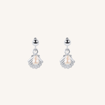 A pair of silver dangle earrings featuring a small shell-shaped charm with a central pearl, suspended from a polished silver round bead, set against a solid off-white background.