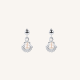 A pair of silver dangle earrings featuring a small shell-shaped charm with a central pearl, suspended from a polished silver round bead, set against a solid off-white background.