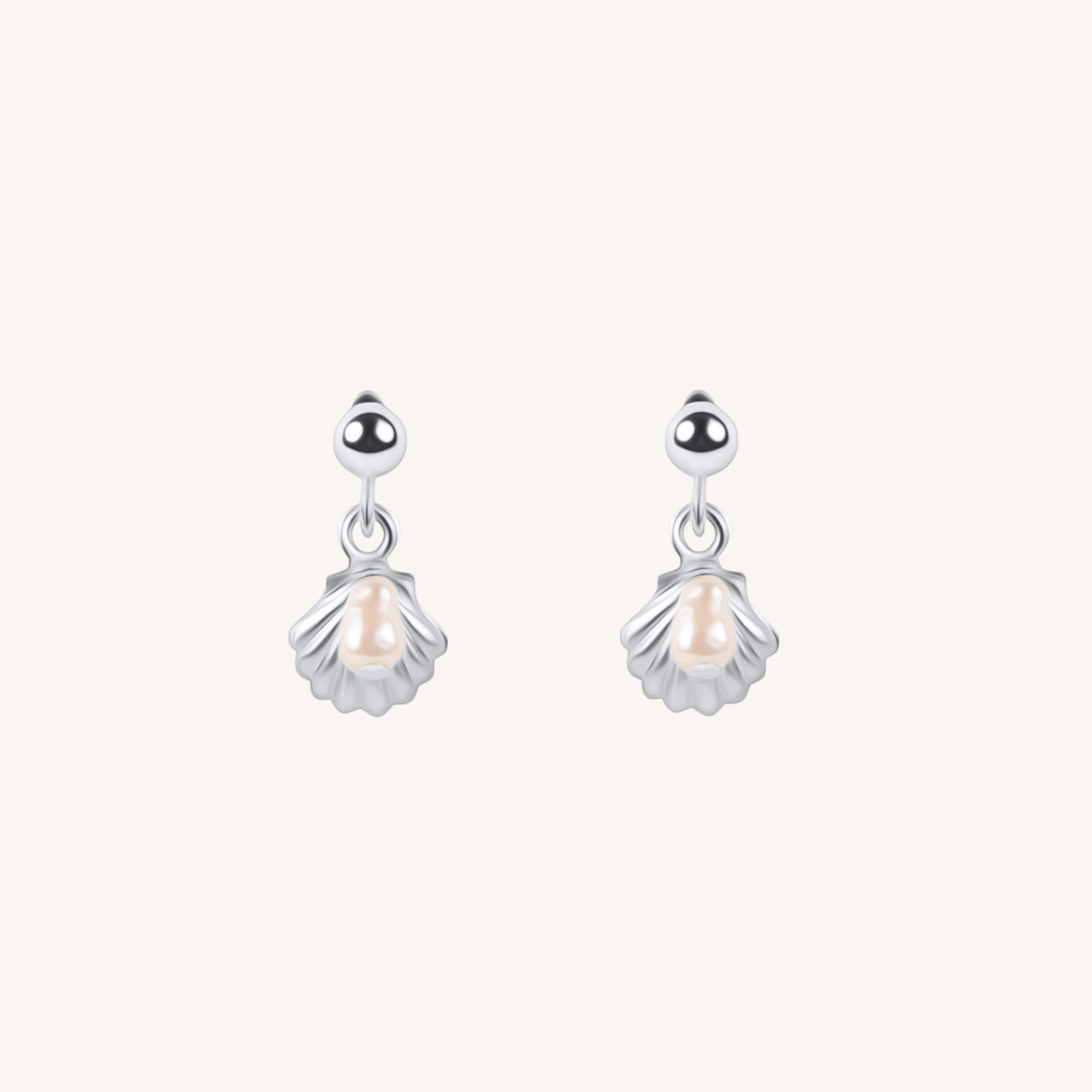 A pair of silver dangle earrings featuring a small shell-shaped charm with a central pearl, suspended from a polished silver round bead, set against a solid off-white background.