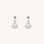 A pair of silver dangle earrings featuring a small shell-shaped charm with a central pearl, suspended from a polished silver round bead, set against a solid off-white background.