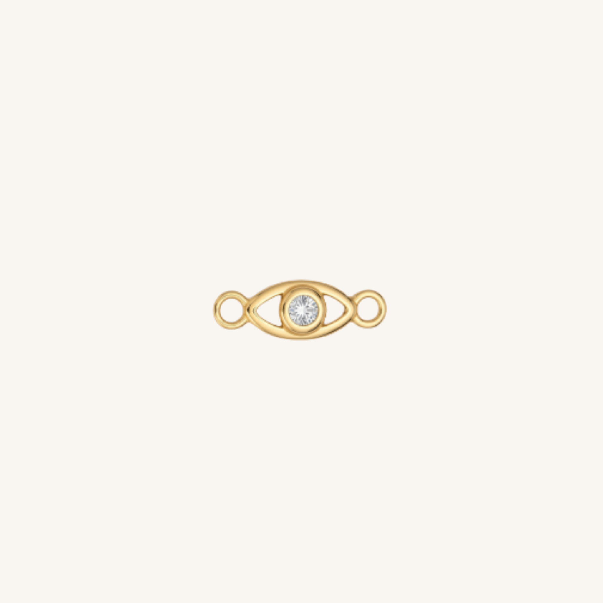A gold eye-shaped charm with a clear round gemstone in the center, set against a solid off-white background.