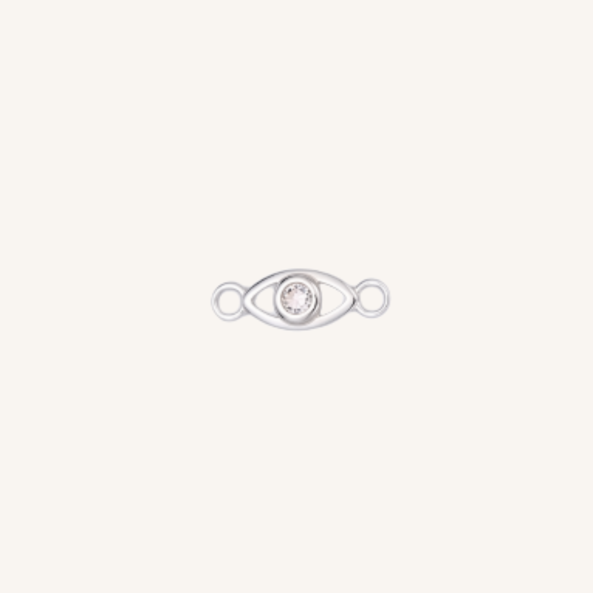 A silver eye-shaped charm with a clear rhinestone in the center, set against a solid off-white background.