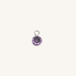 A small round amethyst charm in silver, centered on a light cream background.