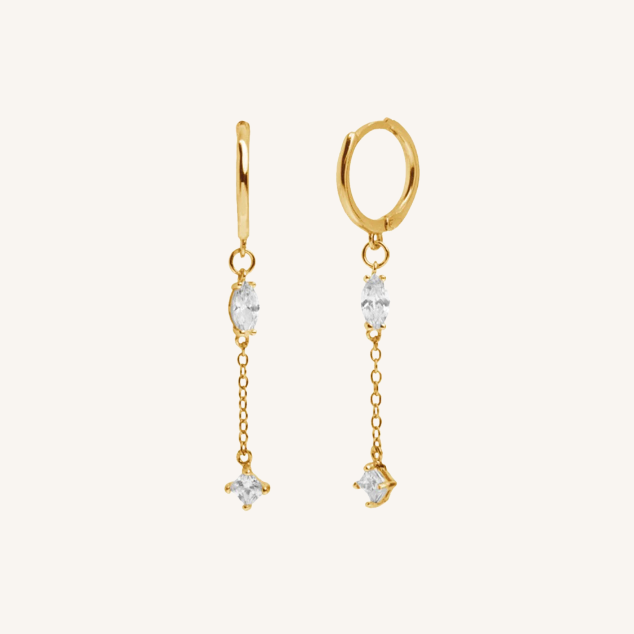 A pair of gold dangle earrings with clear gemstones, displayed on a clean off-white background.