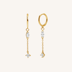 A pair of gold dangle earrings with clear gemstones, displayed on a clean off-white background.