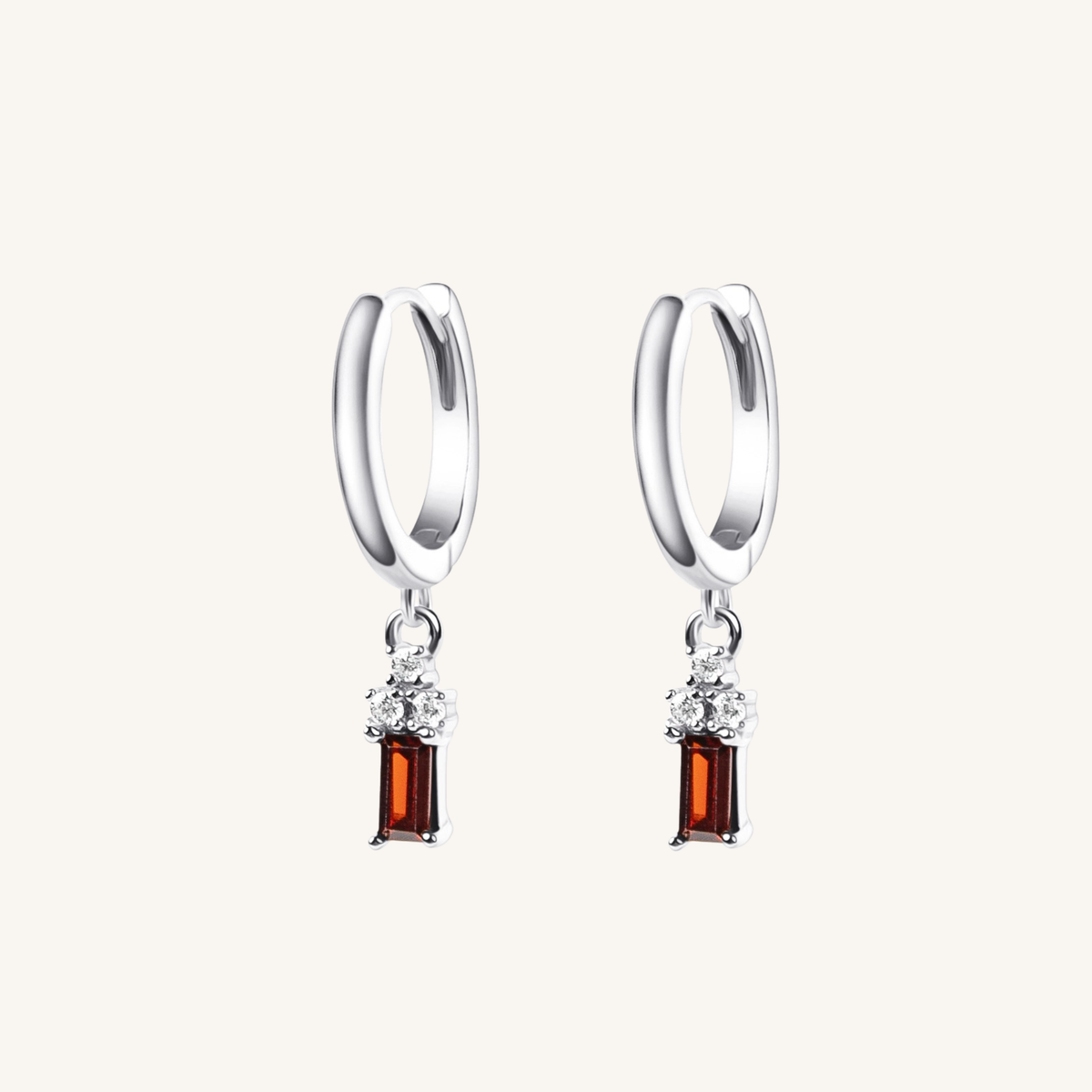 A pair of silver huggie hoop earrings with a dangling rectangular amber gemstone and small clear accent stones, shown on a light cream background.
