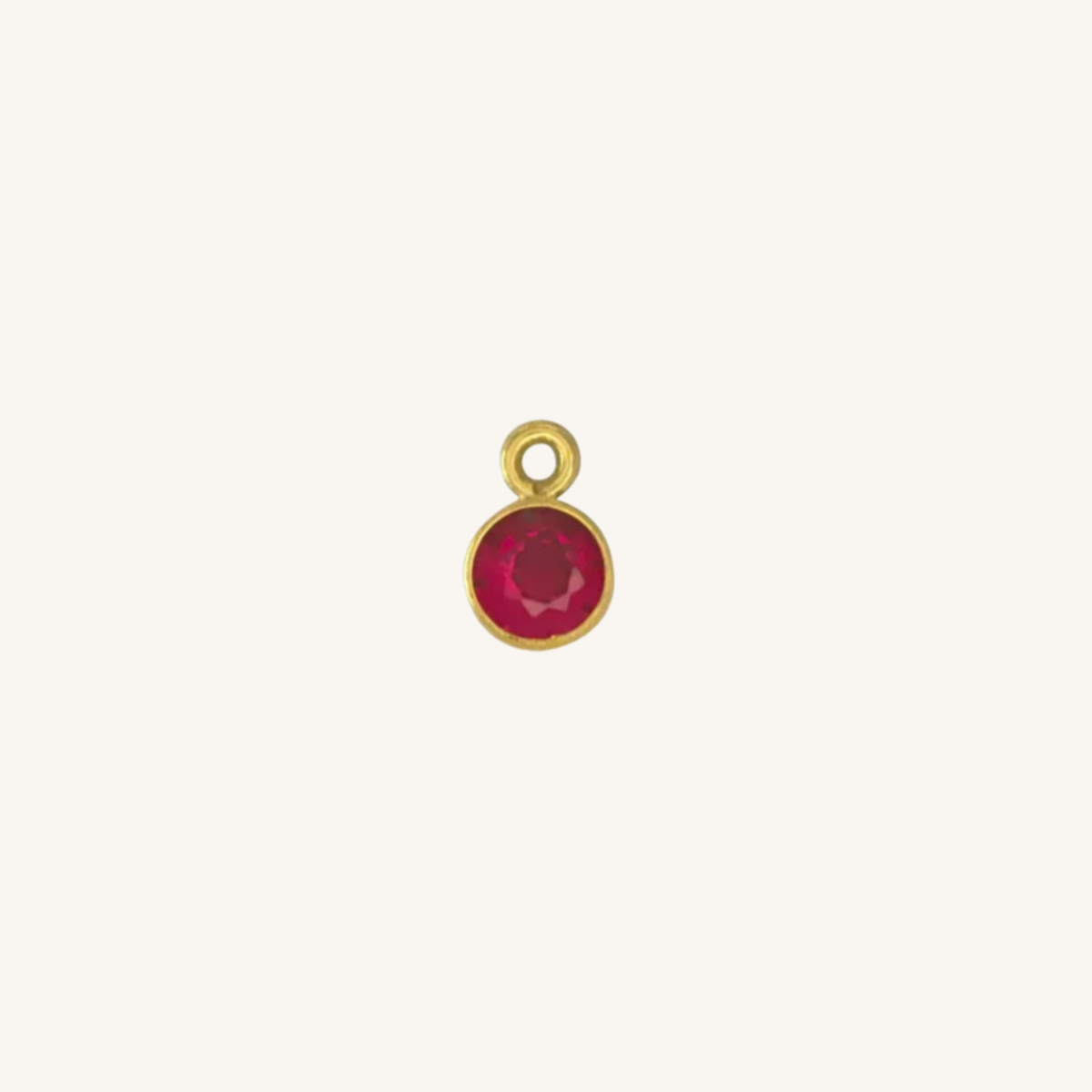 Round ruby charm in gold.