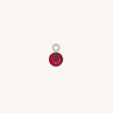 A small round ruby charm in silver, centered on a light cream background.