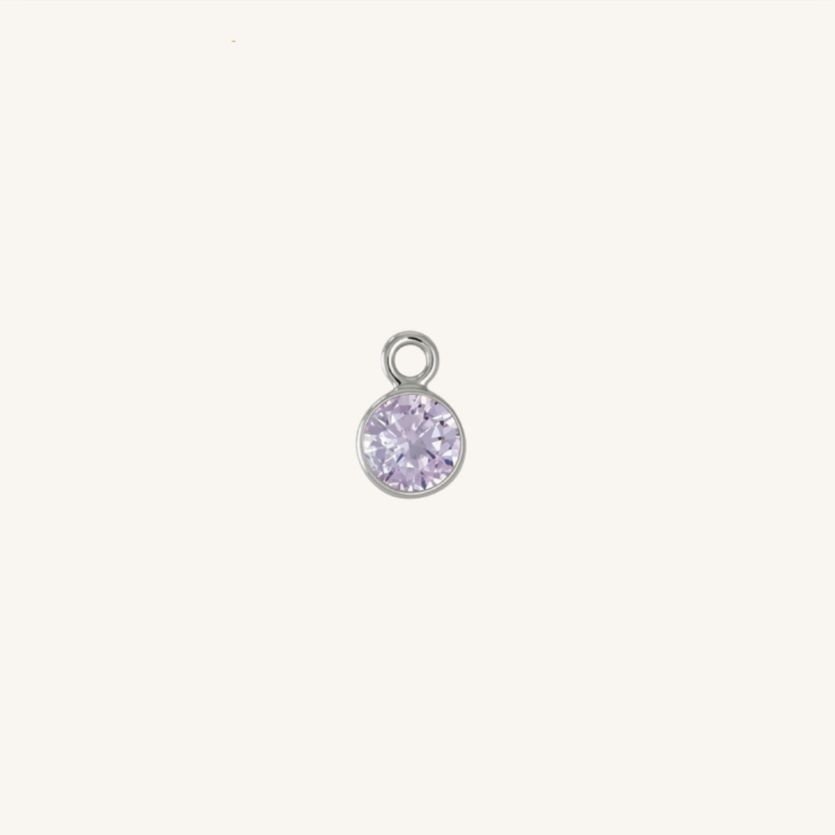 A small round alexandrite charm in silver, centered on a light cream background.