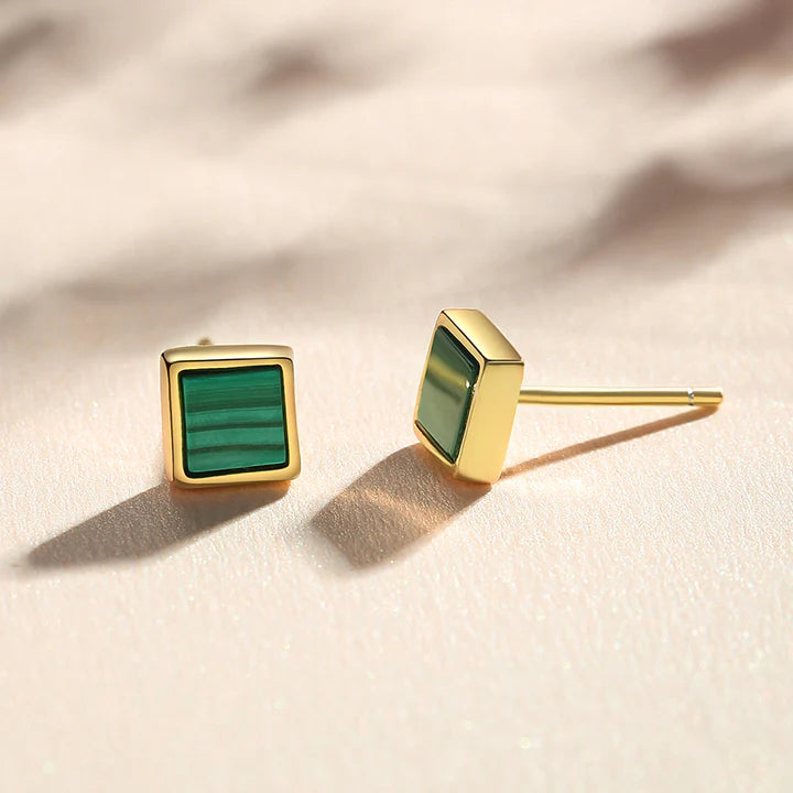 A pair of gold square stud earrings with a green striped inlay, shown on a light cream background.