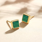 A pair of gold square stud earrings with a green striped inlay, shown on a light cream background.