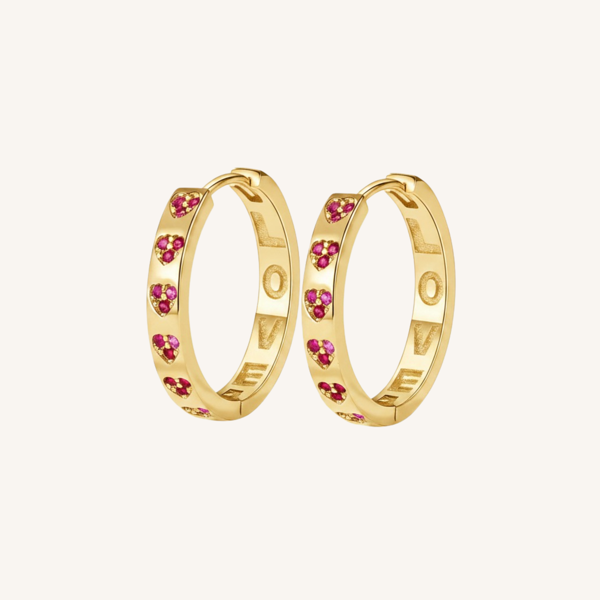 A pair of gold hoop earrings decorated with small pink heart-shaped gemstones, displayed on a clean off-white background.