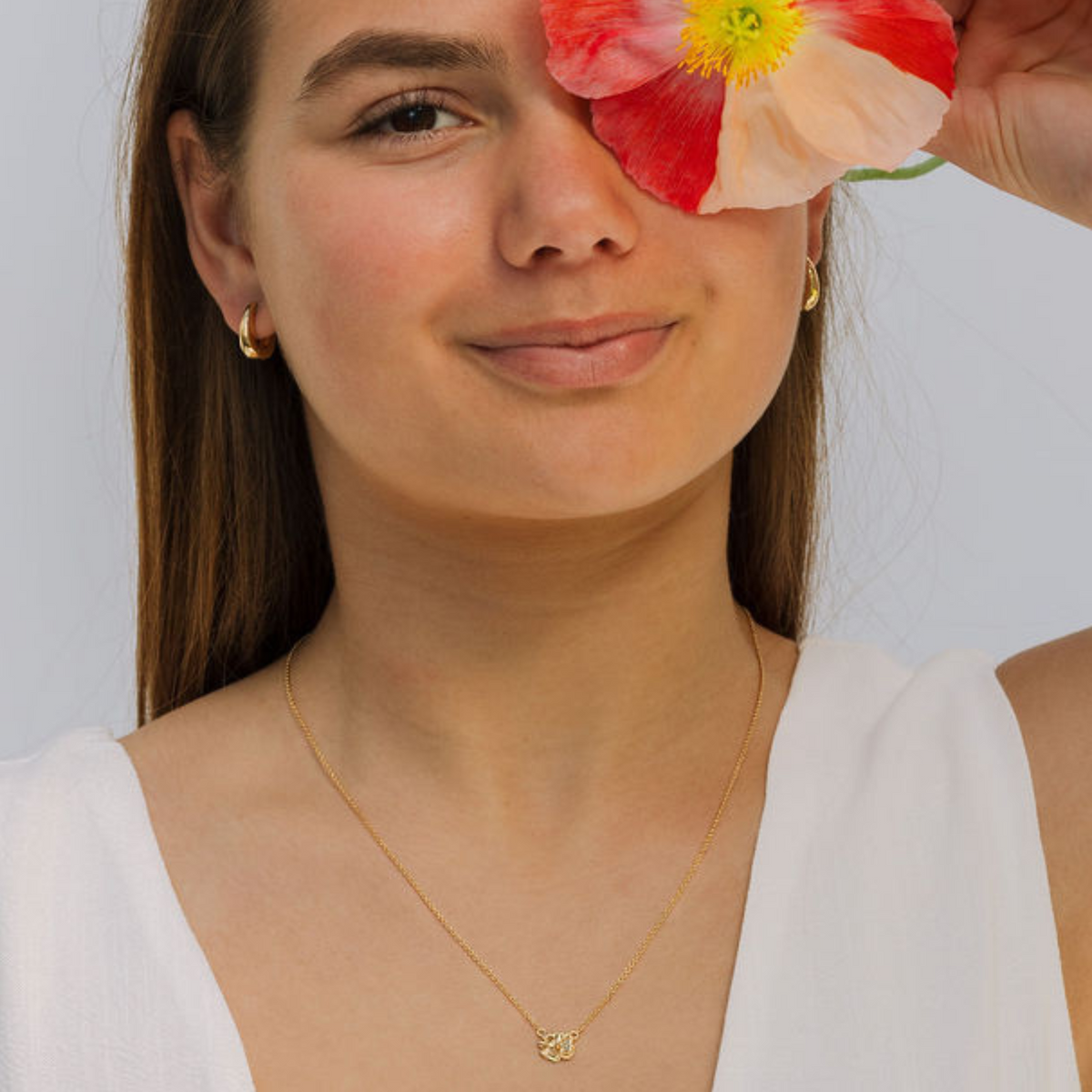 Woman wearing a gold necklace with a white background