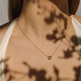 Gold necklace with a pendant worn by a person, with a soft focus background