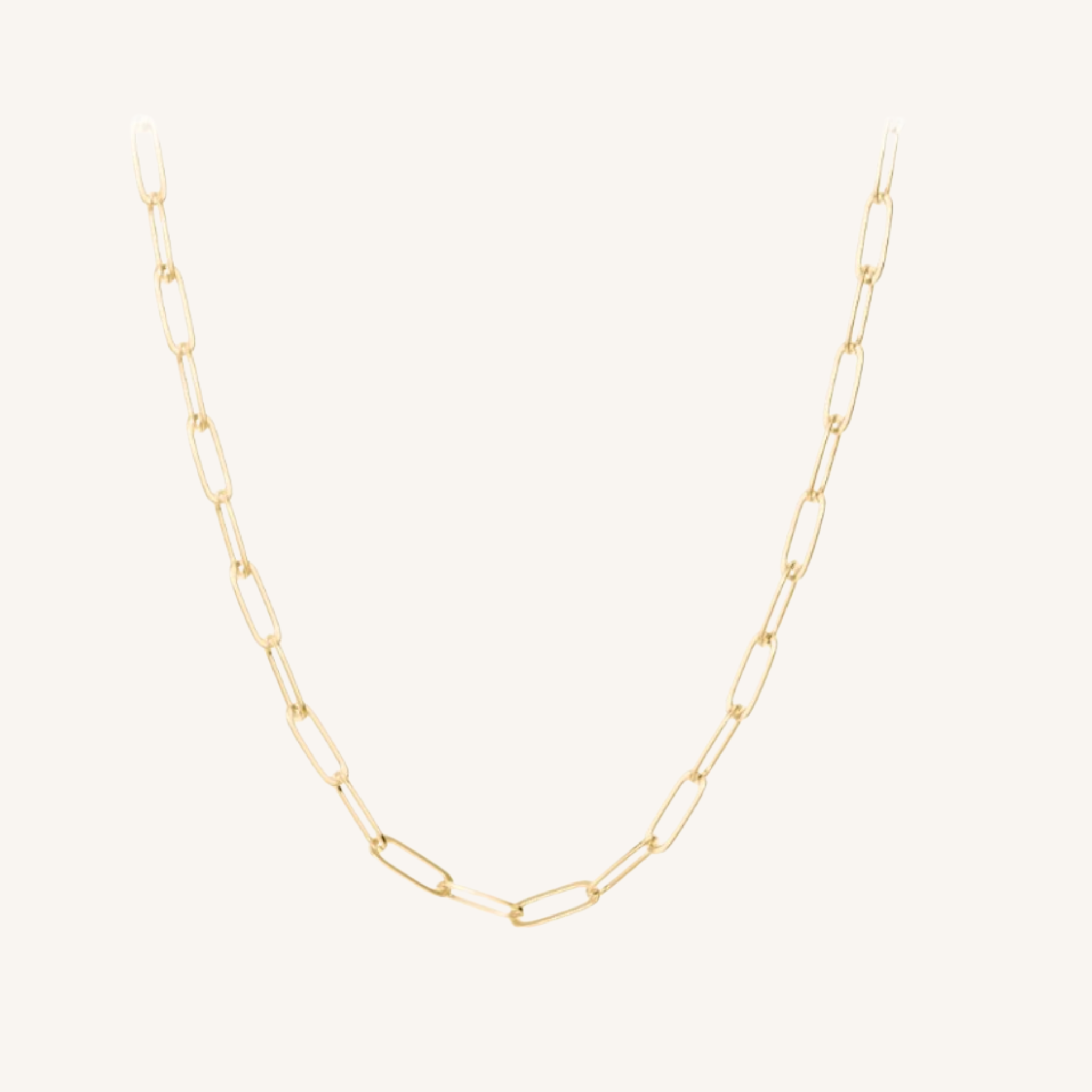 A delicate gold paperclip chain necklace displayed against a solid off-white background.