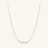 A silver paperclip chain necklace with elongated oval links, displayed against a solid off-white background.