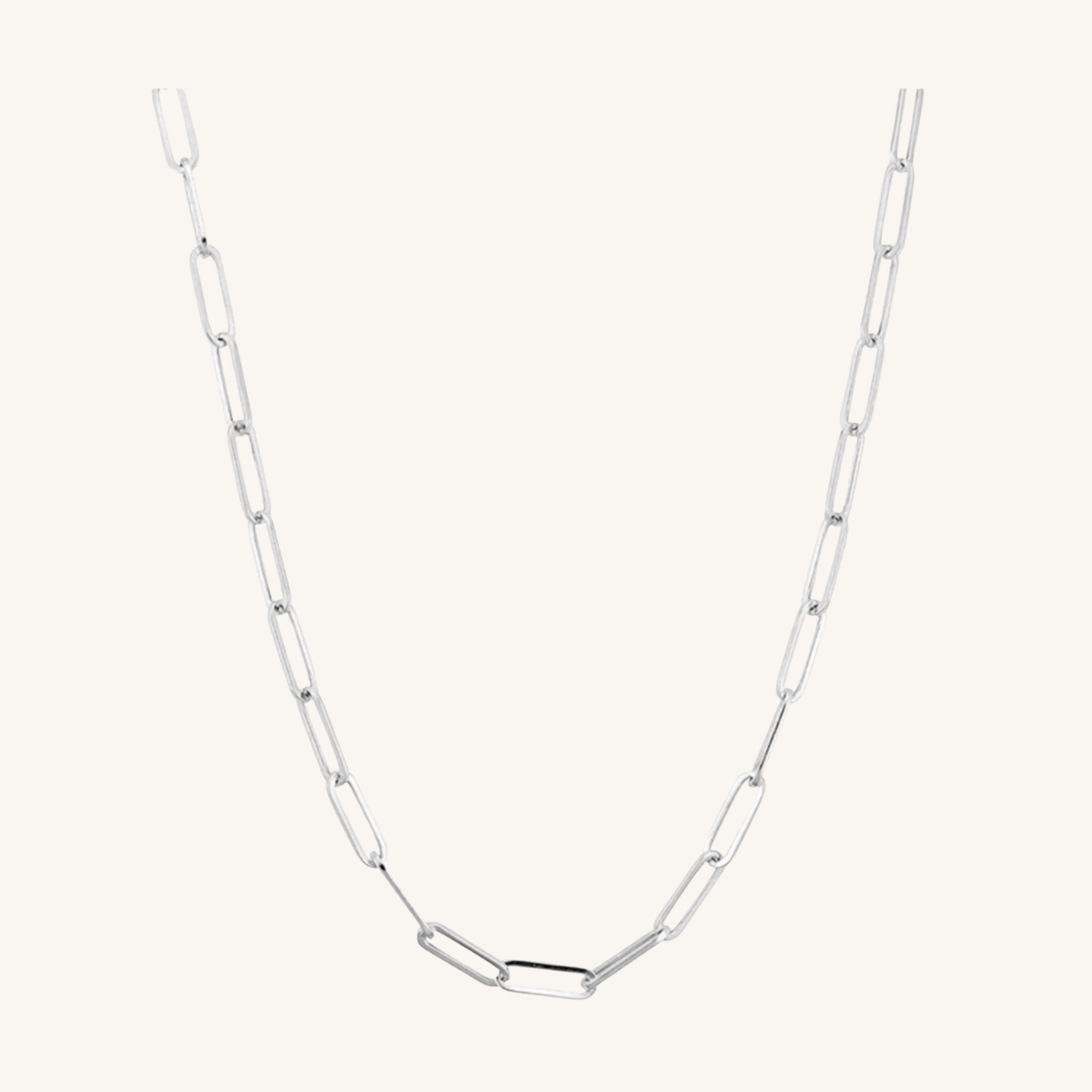 A silver paperclip chain necklace with elongated oval links, displayed against a solid off-white background.