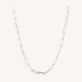 A silver paperclip chain necklace with elongated oval links, displayed against a solid off-white background.