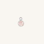 A small round tourmaline charm in silver, centered on a light cream background.