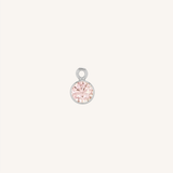 A small round tourmaline charm in silver, centered on a light cream background.