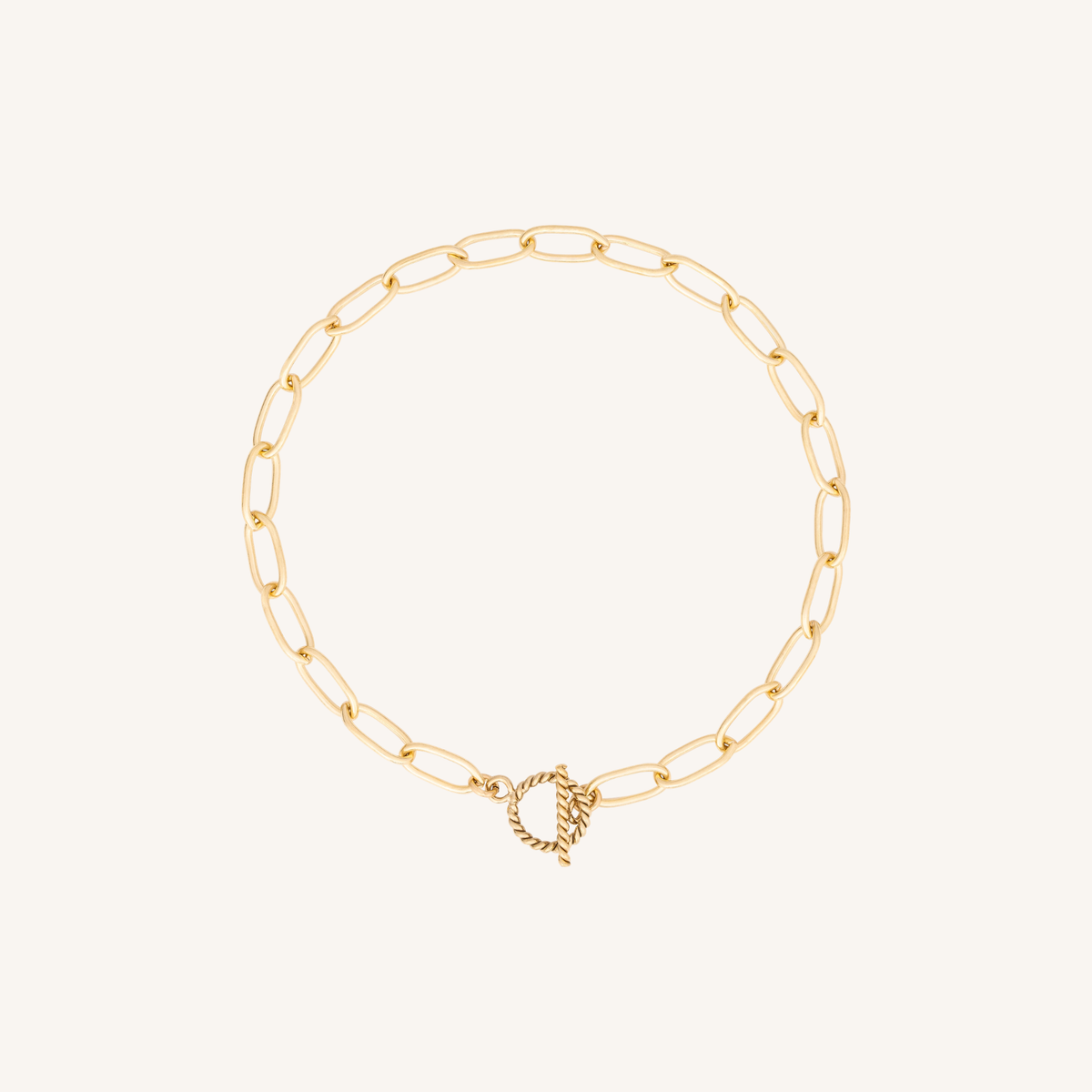 A delicate gold paperclip chain bracelet with a small twisted rope toggle clasp, displayed on a clean off-white background.
