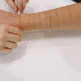 Gold chain necklaces being tried on a person's arm against a white background