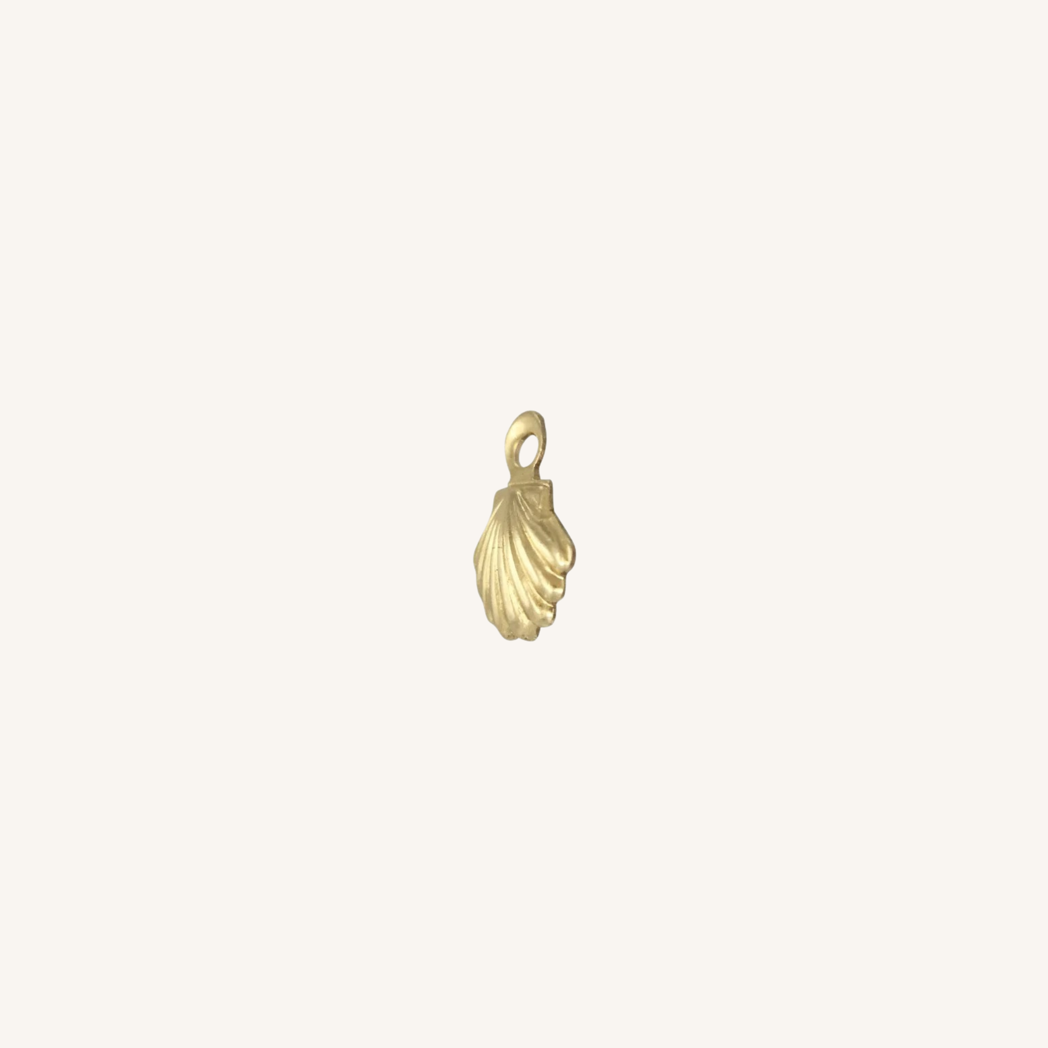 A small gold shell-shaped charm with a loop at the top, centered on a plain off-white background.