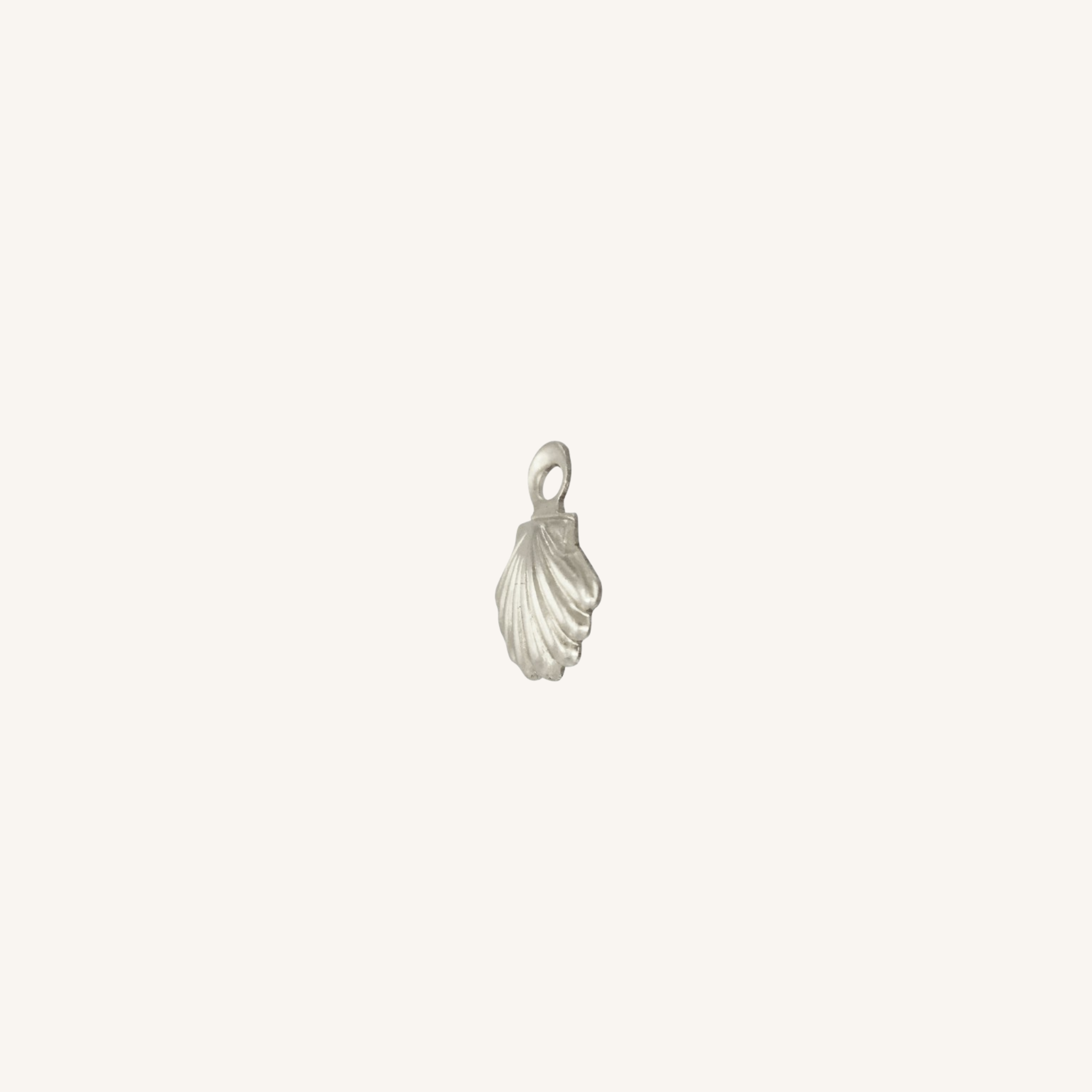 A small silver shell-shaped jewelry charm with a loop at the top, centered on a plain off-white background.