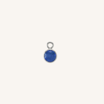 A small round sapphire charm in silver, centered on a light cream background.